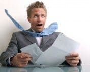 Confused man with tie flying off holding documents and papers – Western Slope real estate concerns.