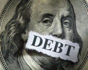 Debt on U.S. dollar bill with torn paper label.