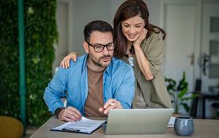 Couple reviewing mortgage insurance documents on a laptop at home in Western Colorado