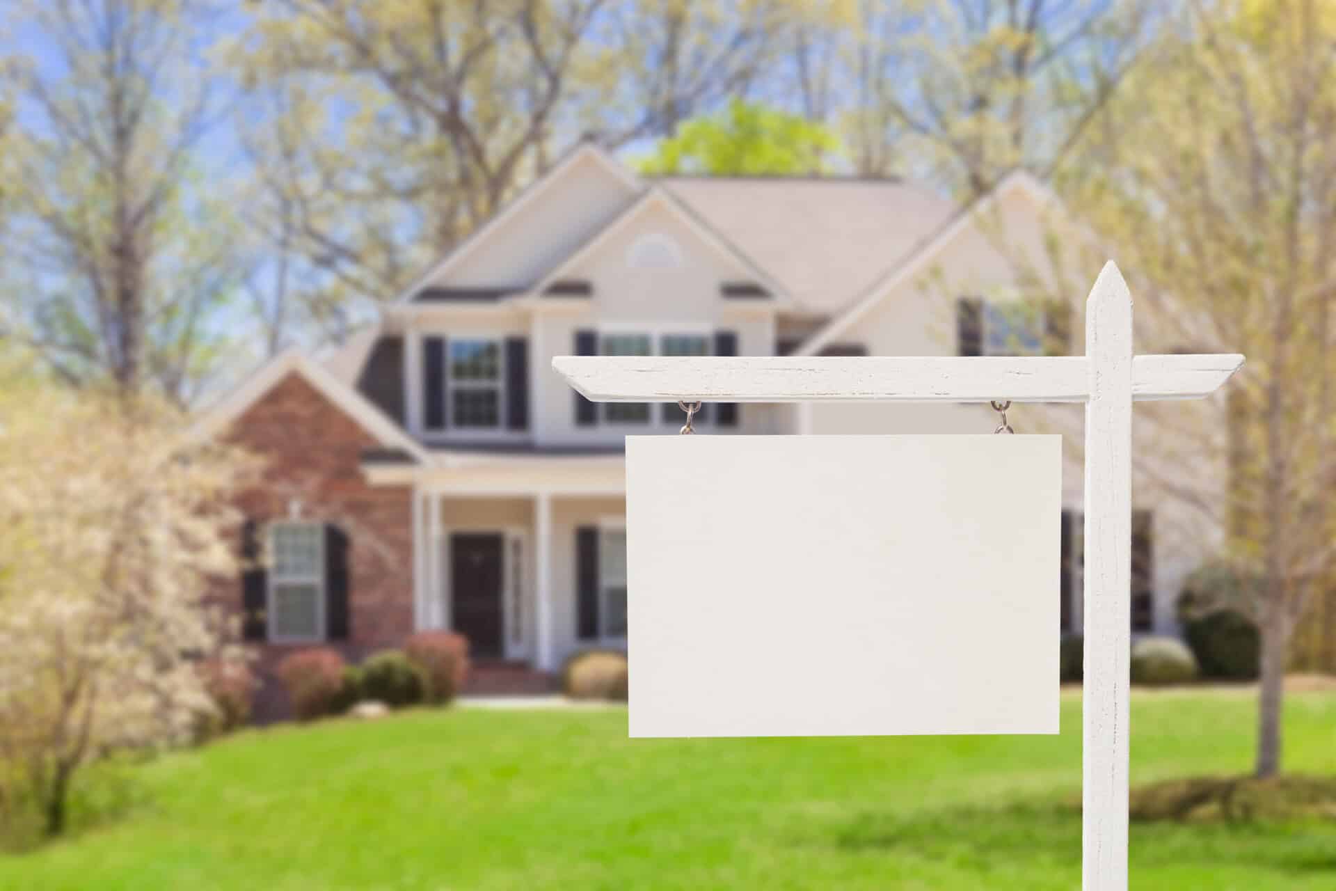Real estate sign in front of a Grand Junction home with a price-reduction rider attached, illustrating the risk of overpricing a listing.